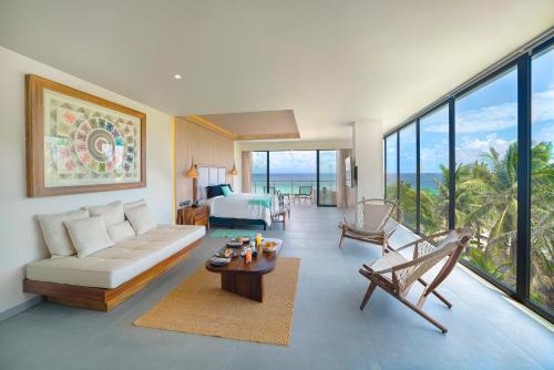 a living room with a couch and a room with the ocean at Mvngata Beach Hotel in Playa del Carmen