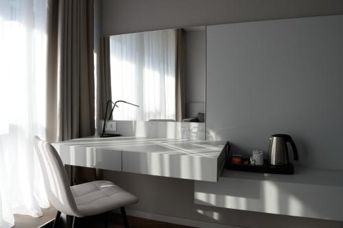 a white kitchen with a white counter and a chair at Premier Hotel Miskolc in Miskolc