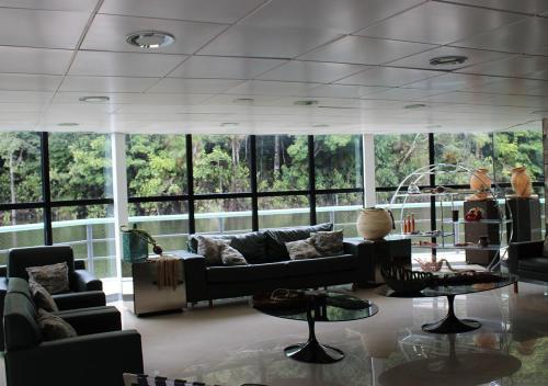 a living room with couches and tables and windows at Uiara Amazon Resort in Manaus