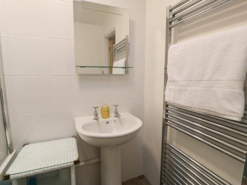 a white bathroom with a sink and a mirror at Llannor in Porthmadog