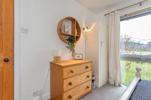 a bedroom with a dresser and a mirror and a window at Inshcraig in Kincraig