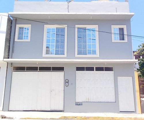 uma casa azul com duas portas de garagem brancas em Departamento ELSA. La Crucecita, Huatulco. em Santa Cruz, Huatulco