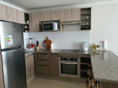 a kitchen with a stainless steel refrigerator and cabinets at Marina Casino Playa in Coquimbo