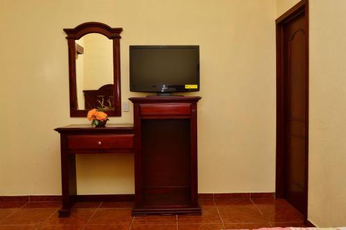 a tv on a stand in a room with a mirror at Hotel Campo Real Plus Tamasopo in Tamasopo
