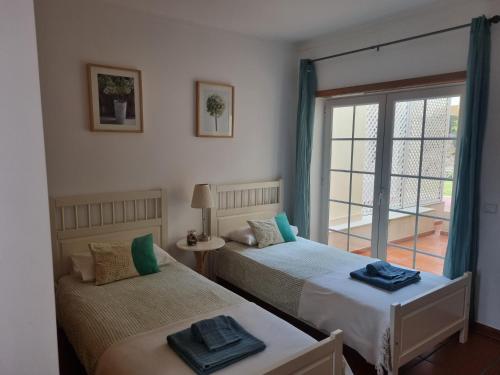 two beds in a room with a window at Praia D'El Rey - Townhouse Dom Duarte in Amoreira