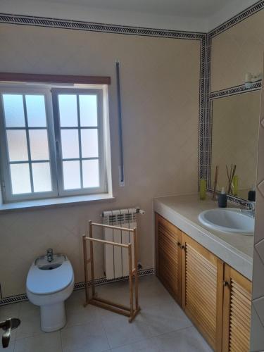 a bathroom with a toilet and a sink and a window at Praia D'El Rey - Townhouse Dom Duarte in Amoreira