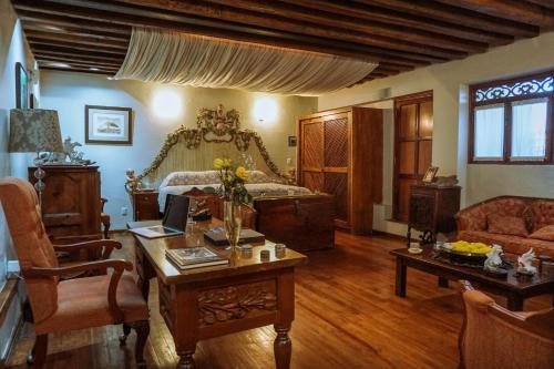 a living room with a bed and a desk and a table with a laptop at Boutique Hotel Casa Cid de León in Oaxaca City