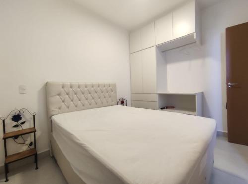 a white bedroom with a large white bed in it at Home Resort - Apto JPII48B Ubatuba in Ubatuba