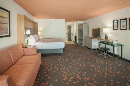 a hotel room with a bed and a desk at Holiday Inn Pensacola - University Area by IHG in Pensacola