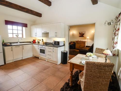 a kitchen with white cabinets and a table at Parlour Barn in Charlton