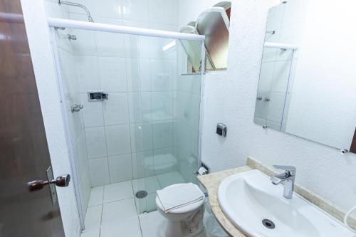 y baño con ducha, aseo y lavamanos. en Hotel Geneve, en Campos do Jordão