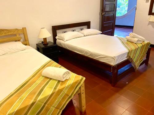 a room with two beds and a table and a lamp at Hotel Minca - La Casona in Minca