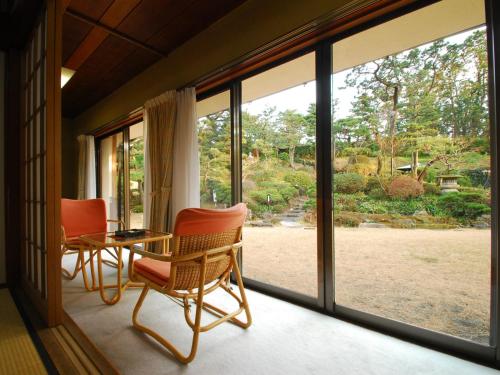 a screened in porch with a table and chairs and windows at Hotel Hagoromo in Shizuoka
