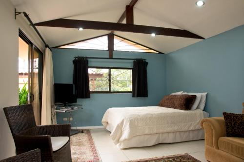 a bedroom with blue walls and a bed with a window at Coffee Garden Ranch Costa Rica in Concepción