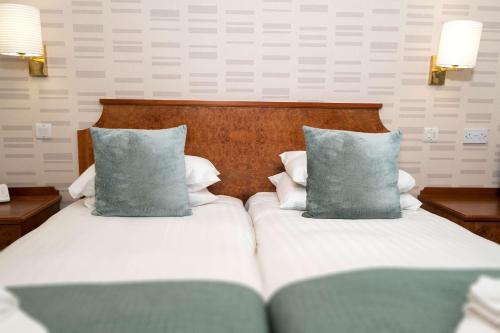 two beds with blue pillows in a hotel room at Pitbauchlie House Hotel - Sure Hotel Collection by Best Western in Dunfermline