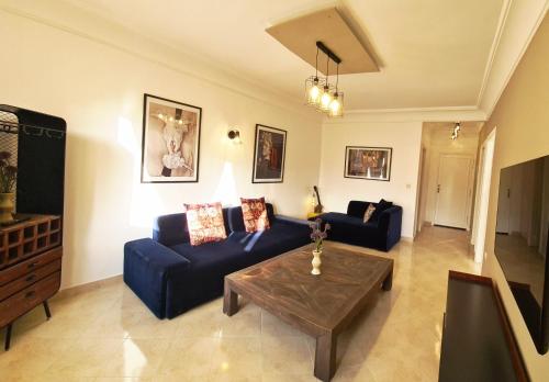 un salon avec un canapé bleu et une table basse dans l'établissement Superbe Appartement à 2 Min de la gare de Tanger et à 5 min de la plage Malabata, à Tanger