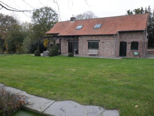 a brick house with a green lawn in front of it at Vakantiehuis Montezicht in de groene heuvels van Dranouter in Heuvelland