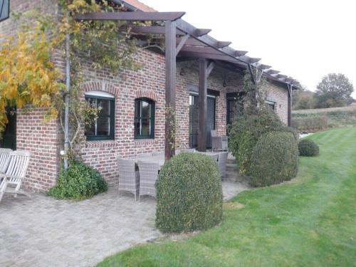 a brick house with a table and chairs in a yard at Vakantiehuis Montezicht in de groene heuvels van Dranouter in Heuvelland