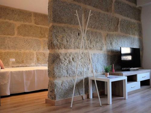 a room with a stone wall with a table and a tv at Apartment in Ourense near Thermal Baths in Ourense
