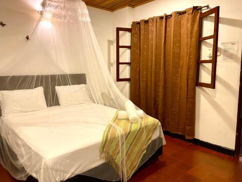 a bedroom with a bed with a mosquito net at Hotel Minca - La Casona in Minca
