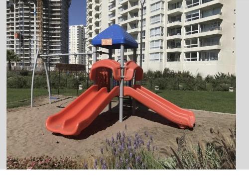 a playground with a red slide and an umbrella at Marina Casino Playa in Coquimbo
