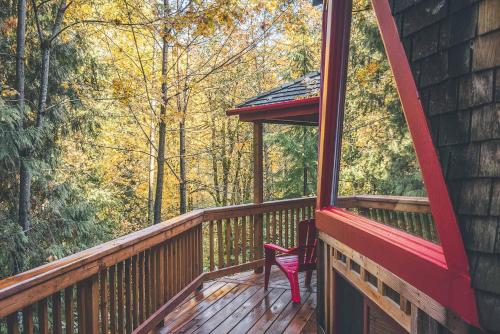 a red chair sitting on a wooden deck with a window at Cedar Creek Hideaway - Meredith Lodging in Welches