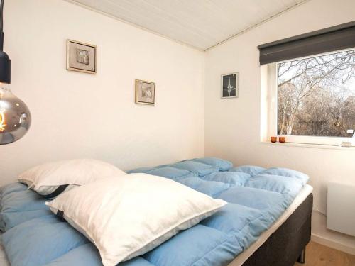 1 cama con sábanas azules en una habitación con ventana en Holiday home Hurup Thy XVIII, en Sønder Ydby