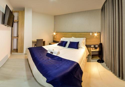 a hotel room with a large bed with blue sheets at HOTEL SAN PEDRO PITALITO in Pitalito