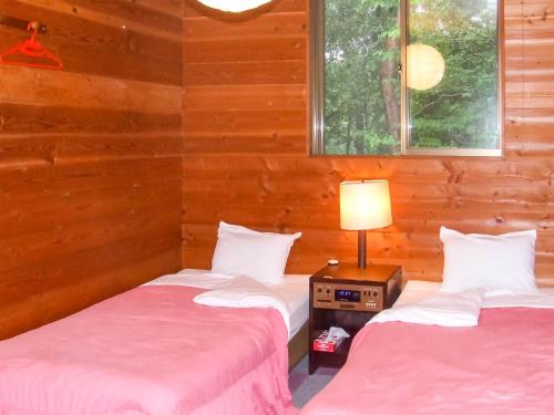 2 camas en una habitación con paredes de madera en Yamanakako Pension Pause en Yamanakako