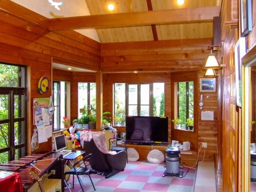 a living room with wooden walls and a flat screen tv at Yamanakako Pension Pause in Yamanakako