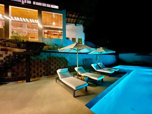 a swimming pool with two chairs and an umbrella at Organica Yoga Shelter in Paquera