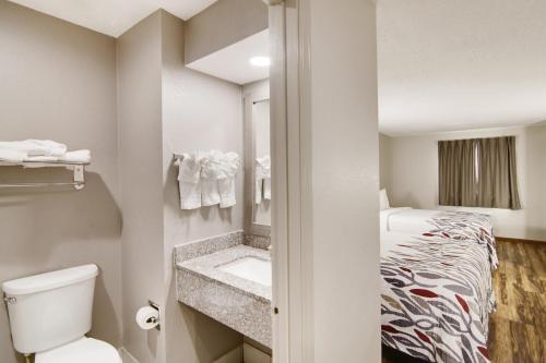 Elle comprend une petite salle de bains pourvue de toilettes et d'un lit. dans l'établissement Red Roof Inn & Suites Pensacola-NAS Corry, à Pensacola