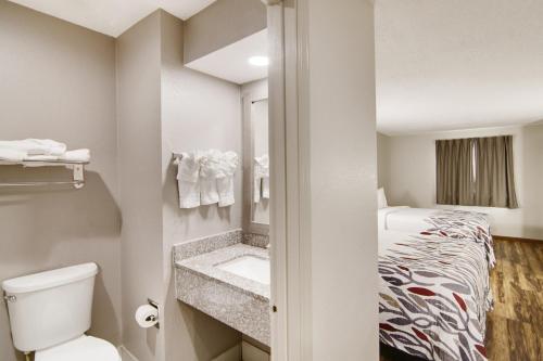 a small bathroom with a toilet and a bed at Red Roof Inn & Suites Pensacola-NAS Corry in Pensacola