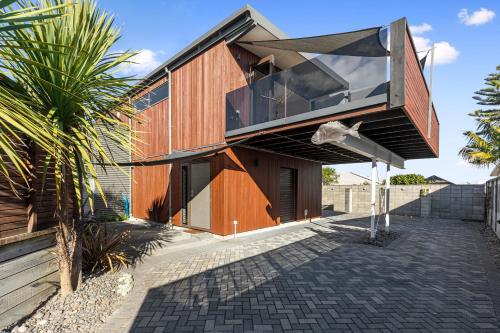 a house with a large window on the side of it at Maranui BeachSide Retreat - Mt Maunganui Home in Mount Maunganui