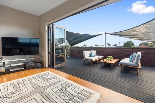 a living room with a large window and a tv at Maranui BeachSide Retreat - Mt Maunganui Home in Mount Maunganui