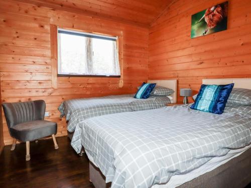 ボドミンにあるHazel Lodgeのベッドルーム1室(ベッド2台、キャビン内の椅子付)
