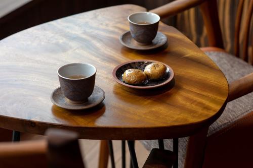 two cups of coffee and a plate of donuts on a wooden table at Shogetsu Grand Hotel in Jozankei