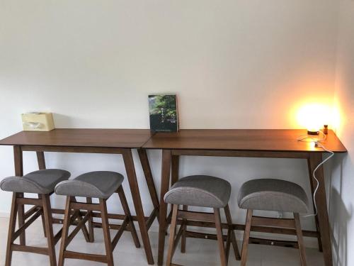 a wooden table with four stools under it with a lamp at Saraswati in Nakijin