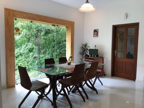 a dining room with a glass table and chairs at Kannur Beachway Homestay in Pāppinisseri