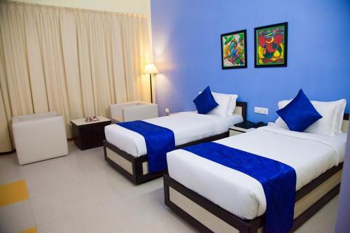 a hotel room with two beds with blue walls at The Kannelite (Hotel Sakchi Vihar By JTDC) in Jamshedpur