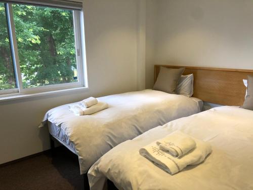 two beds in a room with a window at Ski-in, Ski-out House in Hakuba in Hakuba