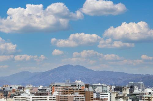 a city with buildings and mountains in the background at HOTEL MYSTAYS Kyoto Shijo in Kyoto