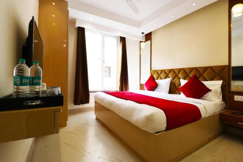 a bedroom with a bed with red pillows and a window at Hotel Leo Saffron - Corporate Stay Pitampura in New Delhi