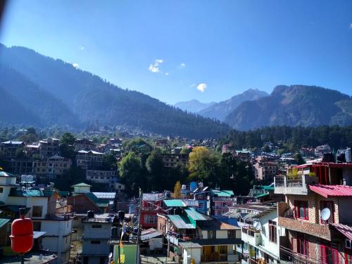 a view of a city with mountains in the background at Hotel Snow Mountain Mall Road in Manāli