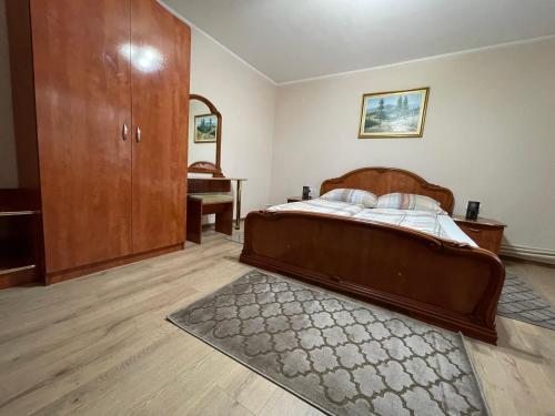 a bedroom with a wooden bed and a dresser at Casa Titiana Suncuius in Şuncuiuş