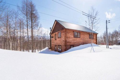 a wooden cabin in the snow in a field at Midori House - walking distance to Rusutsu Resort in Rusutsu