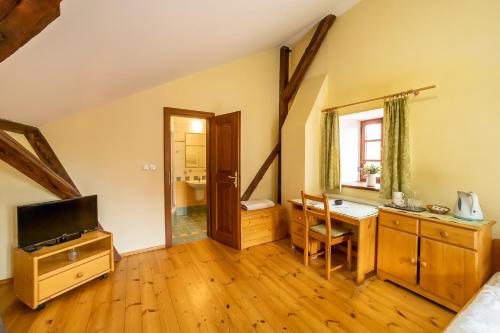 a room with a television and a desk with a table at Penzion Maštal in Český Krumlov