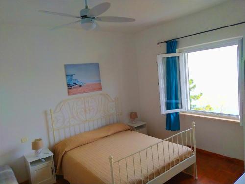 a bedroom with a bed with a ceiling fan and a window at Ghiaie sea view in Portoferraio