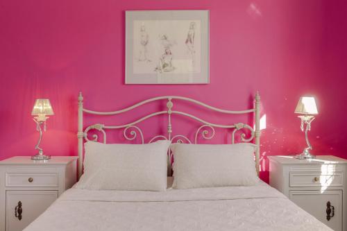 a pink bedroom with a white bed and two night stands at Casa di Mema in Argostoli