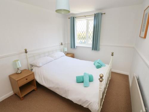 ein Schlafzimmer mit einem weißen Bett und blauen Handtüchern darauf in der Unterkunft Grooms Cottage in Tenby